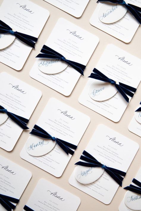 Wedding menu cards, tied with navy velvet ribbon, each menu card with an oval shaped place card written in navy calligraphy. Each menu card with rounded corners and calligraphy in navy ink. Velvet Bow Wedding Invitation, Navy Ribbon Wedding, Velvet Ribbon Place Cards, Navy Place Setting, Personalized Menu Wedding, Place Card With Ribbon, Ribbon Menu Wedding, Velvet Ribbon Wedding Invitation, Black Ribbon Wedding Invitations