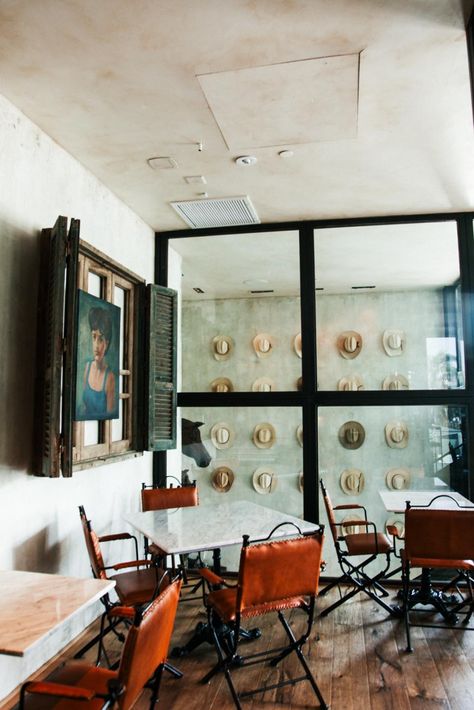 This dining area in Bracero Cocina de Raiz features a wall of steel-framed windows that showcases a view of the staircase. The staircase boasts one of the restaurant's most notable displays, an installation of vintage Bracero hats. Cowboy Restaurant, Cowboy Hat Display, Mexican Restaurant Design, Cowboy Chic, Modern Cowboy, Hat Wall, Hat Display, The Staircase, Vintage Display