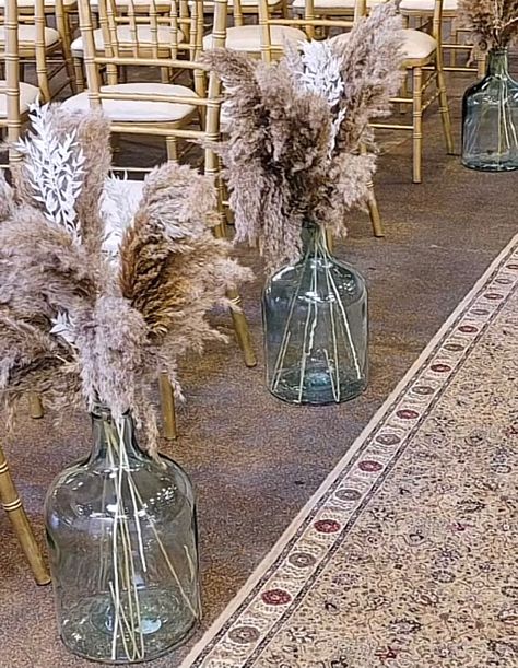 Fluffy pampas grass is displayed in large heavy glass floor vases. Lantern Wedding Ceremony, Glass Jar Centerpieces, Wood Lantern Centerpiece, Jar Centerpiece Wedding, Glass Vases Wedding, Jug Decor, Wedding Jars, Large Glass Jar, Wine Bottle Centerpieces