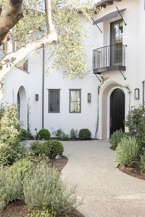 A juliet balcony is fixed over a black arch paneled front door. Spanish Balcony, Spanish Arches, Transitional Home Exterior, Santa Barbara Style Homes, Black Arch, Santa Barbara Style, Flip House, Juliet Balcony, Spanish Modern