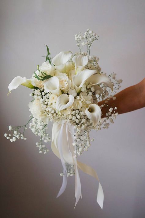 A lily bridal bouquet with calla lilies and baby’s breath. White Jasmine Bouquet, Mother Of Bride Flowers Pin, Gold And White Bouquet Wedding, White Calla Lily Bridal Bouquet, Flower Bouquet Beach Wedding, White Lily Bridal Bouquet, Bridal Bouquet Waterfall, Bridal Bouquet Classic Elegant, Droopy Bridal Bouquet