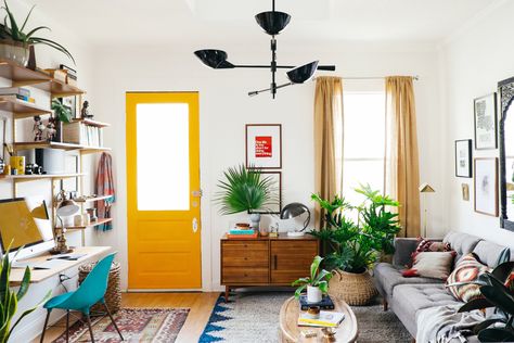 This is my 100 sq.ft. living room makeover I worked on for West Elm. Check  out their blog for more tips! It's a shotgun style home. They're very  popular in New Orleans and dates back to the early 1800s. They're basically  a long and narrow, rectangular house. Ours had the living room in the  front, then kitchen, followed by the dining room, bedroom, and with a  bathroom in the back. The idea is that if you fire a gun at the house, it  would go through each room. A little scary sounding.  I ... Rooms With Plants, Lots Of Plants, Yellow Door, Small Space Design, Bohol, Living Room Makeover, A Living Room, Settee, Small Living Rooms