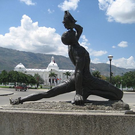 Haiti's Le Negre Marron Statue  The "Negre Marron" is shown with left leg extended (broken chain on his ankle); a machete is in his right hand, and his left hand holds a conch shell to his lips. The conch shell was often used as a trumpet to assemble people. Created by the Haitian sculptor/architect, Albert Mangones (1917-2002) in 1968 or 1969, the statue was commissioned by the Duvalier government to commemorate the slaves who revolted against France. Neg Mawon, Haiti Tattoo, Haitian Culture, Broken Chain, Boat Trips, City Guide, Haiti, Small Towns, Cool Places To Visit