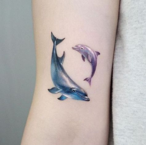 180 Creative Dolphin Tattoos Designs with Meanings (2022) - TattoosBoyGirl Dolphin Wrist Tattoos For Women, Mother Daughter Dolphin Tattoo, Dolphin Tattoo On Thigh, Dolphin Tattoo Mom And Daughter, Dolphin Tattoo Color, 2 Dolphin Tattoo, Dolfin Tattoo Ideas, Delfino Tattoo, Dolphin Tattoo For Women