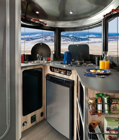 The kitchen features a stove, sink, microwave, and refrigerator, as well as lots of smart storage. Rv Interiors, Travel Trailer Organization, Airstream Basecamp, Airstream Living, Airstream Bambi, Lightweight Trailers, Airstream Rv, Airstream For Sale, Airstream Travel Trailers