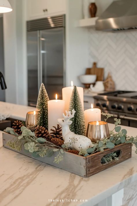 Festive kitchen centerpiece with lit candles, miniature trees, and a porcelain deer in a wooden tray. Christmas Decor For Counter Top, Christmas Decor Inspiration 2024, White And Neutral Christmas Decor, Christmas Decor Ideas In Kitchen, Christmas Apt Decorating, Christmas Kitchen Display, Living Room Table Christmas Decor Ideas, Buffet Decor Christmas, White Table Christmas Decor