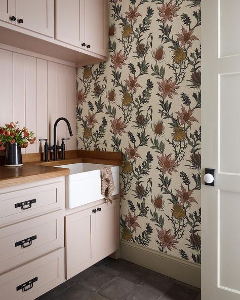 Laundry room features pink cabinets with bronze hardware and a wood countertop with apron sink and an oil rubbed bronze deck mount faucet and pink shiplap trim with bontanical wallpaper. Pink Mudroom, Blush Laundry Room, Pink Shiplap, Pink Laundry Room, Shiplap Trim, Cottage Laundry Room, Pink Laundry, Pink Laundry Rooms, Pink Cabinets