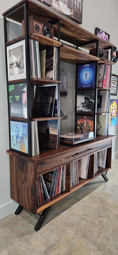 Introducing our Custom Media Console, expertly designed to showcase your cherished vinyl collection with a touch of mid-century modern elegance. Crafted from luxurious black walnut and sleek black metal, this console features distinctive angled legs that enhance its charm. Key Features: Spacious Storage: Accommodates approximately 700 records with lower shelves and a generous solid black walnut drawer. Showcase Design: Upper shelves highlight stunning album artwork, elevating your collection's p Record Player Bookshelf, Vinyl Display Ideas, Stereo Cabinet Ideas, Record Area, Vinyl Console, Vinyl Shelves, Vinyl Record Storage Diy, Modern Record Console, Record Player Setup