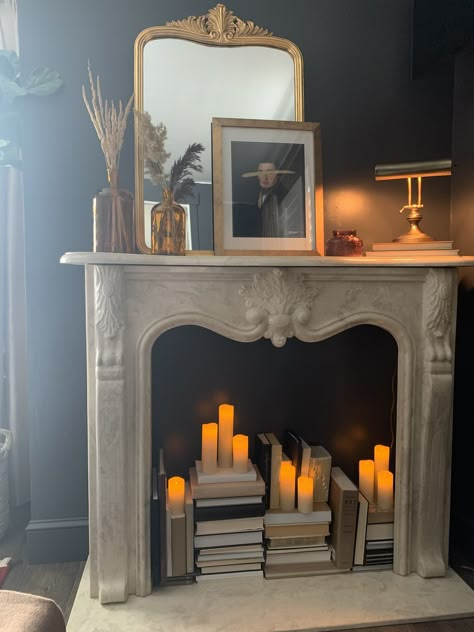 Mantle And Fireplace Decor, Faux Fireplace Fairy Lights, Books Inside Fireplace, Mock Fireplace Mantle, Candlesticks In Fireplace, Faux Fireplace With Candles Inside, Fireplace Mantle Bookcase, White Faux Fireplace, Summer Fireplace Ideas