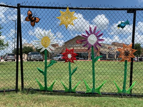 Flowers that I crocheted displayed on the fence that I yarn bomb at the Fairfield Town Center in Cypress, TX. Crochet Fence, Yarn Fence Art, Chain Link Fence Flowers, School Fence Decorations, School Fence Art, Chain Link Fence Art School, Fence Weaving, Fancy Fence, Fence Art