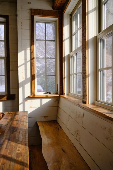 The smell of wood and coffee: This breakfast nook captures organic elegance with its live edge, dark wood benches, and harmonious light paneling. Every detail, down to the craftsman-style window frames, invites you to settle in, savor a coffee, and embrace the warm morning light. Explore more at https://excelsiorwood.com Oak Window Frames, Natural Wood Trim Windows, Light Wood Window Trim, White Window Wood Trim, Wood Framed Windows Interiors, Walnut Window Trim, Wood Trim Windows Interior, Cedar Trim Interior, White Windows With Wood Trim