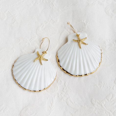 Sea-inspired shell earrings are a must-have in your seasonal wardrobe. They would love to be with you to enjoy the sandy beach and ocean waves. Every porcelain shell is moulded and handcrafted from a natural clam shell. Shell edges are hand-painted with gold lustre. Please handle our porcelain shells with care as they can be quite fragile.Material: Handmade porcelain with gold lustre; Gold plated; Gold filled ear hoops. Gold- or silver-plated colour will fade over time. This is a normal result f Seashell Jewelry Diy, Diy Earrings Easy, Art Coquillage, Ocean Inspired Jewelry, Sea Jewelry, Shell Crafts Diy, Seasonal Wardrobe, Hoops Gold, Seashell Jewelry