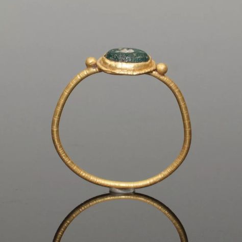 LOVELY ANCIENT ROMAN GOLD RING. ANCIENT ROMAN GOLD RING. DATES: CIRCA 2nd CENTURY AD. SUPPORTING A CENTRAL OVAL BEZEL SET WITH AN IRIDESCENT GREEN GLASS STONE. HAVING A SOLID BAND..#jewelrylover #handcraftedjewelry #jewelryinspiration #jewelrydesign #jewelryobsessed #jewelryoftheday #jewelrygoals #jewelryfashion #jewelrytrends Ancient Silver Jewelry, Sun Outfits, Ancient Gold Ring, Storm Comic, Black Nativity, Ancient Rings, Lost Wax Jewelry, Etruscan Jewelry, Medieval Ring