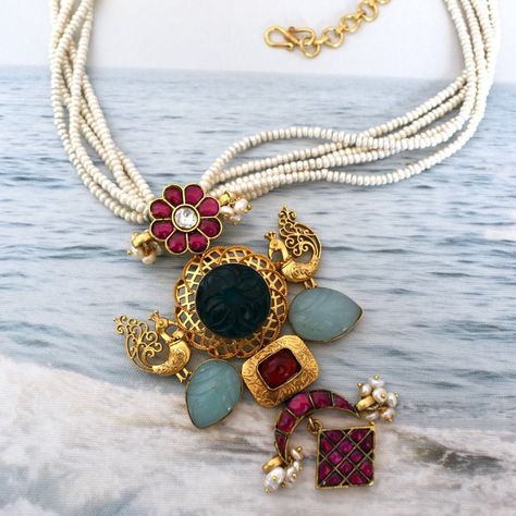 This necklace is designed to make a bold statement, featuring a beautiful bold pendant with a varied range of motifs. The beautiful pendant features a plain metal intricate peacock adorned on both sides with a carved greenstone in the center. The pendant also showcases intricate florals, crescent-shaped motifs, and lattice work, all adorned with premium quality semi-precious stones.The pendant is suspended from a series of pearl strands. The bottom of the necklace is finished with stunning pearl beading, which adds an extra touch of glamour and luxury to the overall design. Moti Pendant Set, South Indian Temple, Fancy Jewelry Necklace, Pearl Beading, Handmade Gold Jewellery, Silver Jewellery Indian, Horse Necklace, Silver Lockets, Jewelry Design Necklace