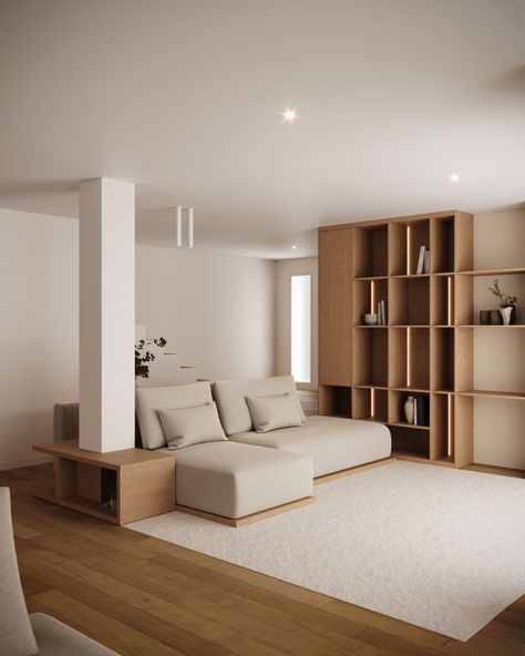 Modern living room with a clean, minimalist aesthetic. 
A beige sectional sofa is placed against a pillar, complemented by a wooden side table. The space features a large wooden bookshelf with decorative items, adding warmth to the neutral tones. The light wood flooring and soft rug create a cozy atmosphere, while recessed lighting highlights the room's simple yet elegant design. Wood Columns Interior, Pillar In Living Room, Clean Minimalist Aesthetic, Light Wood Flooring, Columns Interior, Sectional Sofa Beige, Wood Column, Beige Sectional, Wooden Bookshelf