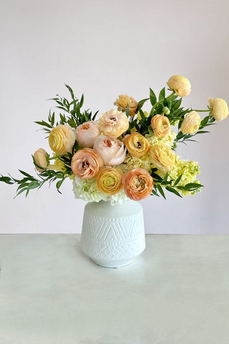 A charming spring flower arrangement boasting the freshest blooms in the prettiest pastel hues. This design delights with peach garden roses, buttercream ranunculus, lemon lilacs, and clouds of white hydrangeas presented in a stylish white ceramic vase. Featured Flowers: Ranunculus, Garden Roses, HydrangeasRecommended for: Birthday, Get Well, Just Because, Congratulations, Thank You, New Baby Includes: Free Message CardDelivery: Guaranteed same-day flower delivery in Santa Monica, Los Angeles, and Orange County. Rose Flower Arrangements Vases, Garden Style Floral Arrangements, Just Because Flowers, Pink And Yellow Flowers, Pastel Flower Arrangements, Summer Floral Arrangements, Spring Floral Arrangements Centerpieces, Yellow Flower Arrangements, Blue Flower Vase