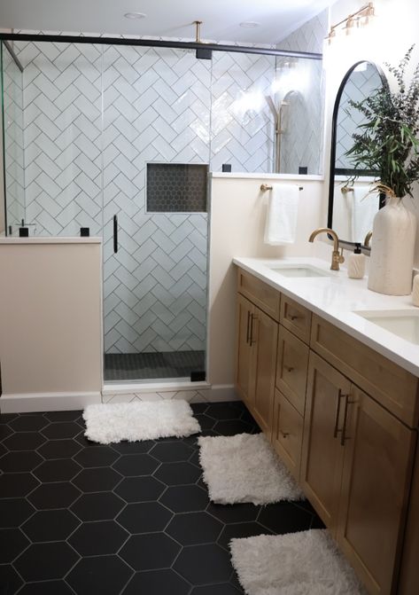 This beautiful bathroom features hexagon floor tiles with coordinating hexagon mosaic in the shower inset. The dark tiles are nicely juxtaposed against the white subway tiles in a herringbone pattern. Bathroom With Black Hexagon Tile, Black Hexagon Flooring Bathroom, Bathroom Dark Hexagon Tile Floor, Charcoal Floor Bathroom Ideas, Dark Tile Bathroom Floor White Walls, Black Herringbone Bathroom Floor, Black Hex Shower Floor, Black Hexagon Tile Bathroom Floor Ideas, Gray Hex Tile Bathroom Floor