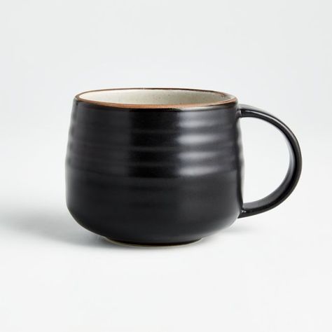 Modern and restrained in form, expressive and rustic in glaze. The artisan's hand is authentically reproduced in this stoneware pattern designed exclusively for Crate and Barrel by ceramic artist and designer Kathy Erteman at her 18th Street studio in New York City. A contemporary matte black exterior contrasts the rustic beauty of a shiny, speckled white glazed interior ringed with the subtly raised spiral associated with hand-thrown pieces. A raised clay rim features a sandy glaze that evokes Black Ceramic Mug, Stoneware Mug, Clay Coffee Cup, Wood Mug, Handmade Dinnerware, Best Coffee Mugs, Black Mugs, Custom Cup, Ceramics Ideas Pottery