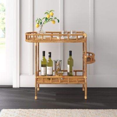 Serve sangria and make mocktails while standing by this eye-catching bar cart that brings the party to any room in your home. Crafted completely from solid bamboo, it comes in a natural brown tone that places the focus on its eco-friendly materials and breezy coastal design. The upper shelf has a rounded side, while the lowest one is rectangular. A small middle shelf on the outside is a great holder for smaller accessories. We love the guardrail-like edges that help keep bottles, glasses, and mo Cute Bar Cart, Bar Cart Aesthetic, Small Bar Cart, Bar Cart Wood, Bar Corner, Rattan Bar Cart, Wood Bar Cart, Gold Bar Cart, Serving Cart