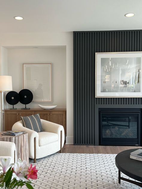 Black & White Design Aesthetic is showcased in this stunning living room. The floor-to-ceiling vertical black paneling surrounding the fireplace is a show stopper that definitely grounds the space! The beautiful oak built ins are great for storage and are styled with minimal decor! New Construction | Home Trends 2024 | Home Design | Minnesota Home Trends | Black & White Design Aesthetic Fireplace With Black Built Ins, Fireplace Built Ins Modern, Black And White Interior Aesthetic, Black Floor To Ceiling Fireplace, Black Fireplace Living Room Decor, Black Fireplace Built Ins, Black Wood Panel Fireplace Wall, Modern Black Linear Fireplace, Black Fireplace With Built Ins