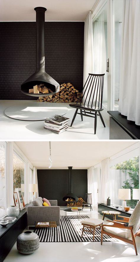 This modern living room features a hanging black fireplace, a black tile accent wall, modern furniture, light grey floors and a pale pink ceiling. Black Fireplaces, Modern Chic Living Room, Modern Living Room Black, Tile Accent Wall, Hanging Fireplace, Black Accent Walls, Modern Family Rooms, Black Fireplace, Living Room Drapes