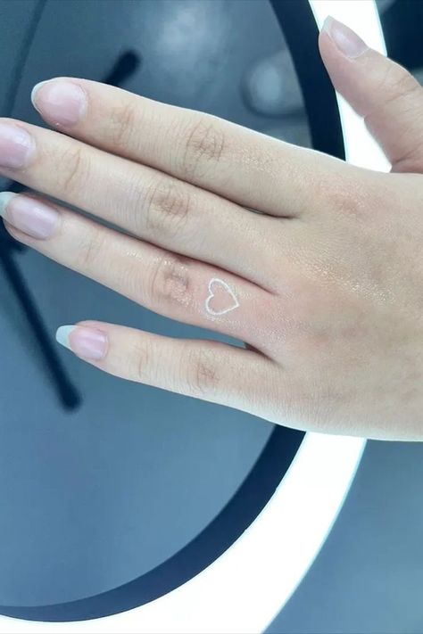 Hearts make ideal finger tattoos because they can be any size and are a recognisable icon. We love this delicate white heart on the front of the finger, 📸 d2mtattoo_ Finger Tattoo Idea, White Heart Tattoo, White Finger Tattoos, Heart Finger Tattoo, White Heart Tattoos, Scratch Tattoo, Heart Tattoo On Finger, Love Heart Tattoo, Hand And Finger Tattoos