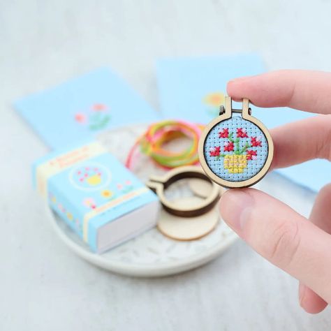 PRODUCT DESCRIPTION     Discover the charm of DIY crafting with our Miniature Cross Stitch Kit, tailored for both beginners and expert stitchers. This delightful kit is themed around vibrant flowers, featuring everything you need for a fun and enjoyable project. Choose to make one of the four deliciously easy designs including: A small sunshine yellow sunflower A tiny sprig of colorful daisies A mini bowl of red rose buds A cheeky little pink daisy in a red flower pot. With their cute designs and pretty colors, these designs won't fail to win love and affection which ever your choose. All this is presented in a tiny matchbox! This matchbox fits through a standard letterbox.   The kit includes:    * A 7cm x 7cm square of pristine white 14pt Aida   * A size 24 tapestry needle crafted for eas Tiny Cross Stitch Flower, Tiny Cross Stitch Flowers, Tiny Cross Stitch Patterns Minis, Miniature Cross Stitch, Mini Rosa, Hoop Frame, Easy Designs, Cross Stitch Beginner, Tiny Cross Stitch