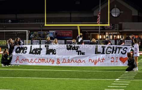 a paper banner spelling “one last time under the lights homecoming and senior night ‘21” is held by cheerleaders on a football field with football players preparing to run through it Senior Football Banner Ideas, Senior Night Banners Football, Senior Night Run Through Signs, Football Banners Run Through, Senior Night Banner, Senior Football Banners, Run Through Signs, Cheer Banners, Football Banners