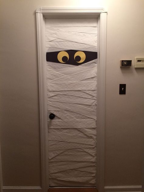 We love Halloween at our house.  It's getting more and more fun as our sons are getting older and more independently involved as adults.  Our 18 year old offered to help decorate our home this year, and we opted for a quick fun fix for our downstairs bathroom door.  Turn it into a mummy!   The project started way back, actually, when I decided to paint all our woodwork, doors included, white.  Here's a picture of what our doors and trim used to look like.  Our house is 1949, with a 201… Mummy Door, Mummy Craft, Wall Bookshelves Kids, Map Wrapping Paper, Doors And Trim, Halloween Classroom Decorations, Mummy Crafts, Summertime Decor, Autumn Craft