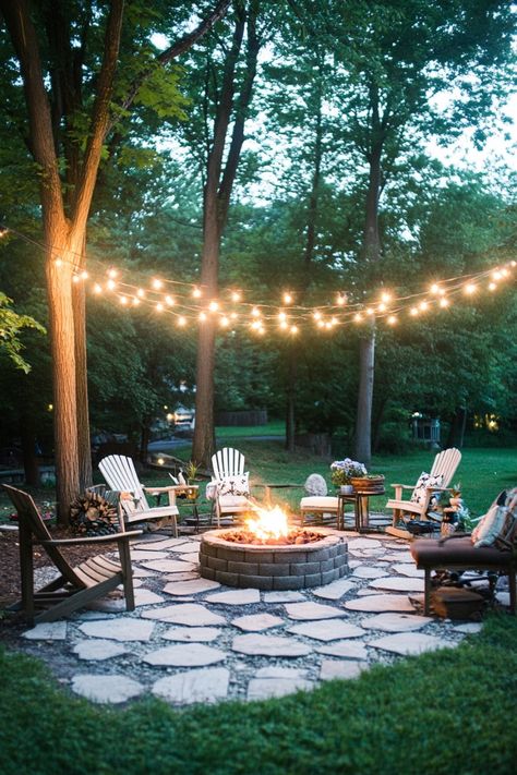 Backyard fire pit area surrounded by Adirondack chairs, lit by string lights. Front Yards Diy, Outdoor Fire Pit Area, Landscaping Around House, Fire Pit Landscaping, Cozy Backyard, Fire Pit Area, Fire Pit Designs, Backyard Lighting, Fire Pit Patio