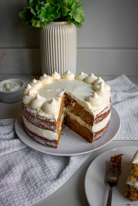 A carrot cake with two tiers and cream cheese frosting with a slice cut out of it. The slice is sitting on a plate next to the cake. Red Velvet Carrot Cake, Names On Cakes Ideas, Cake Decorating Rustic, Tiered Carrot Cake, Cute Carrot Cake Decorations, East Birthday Cakes, Cake Decorating Carrot Cake, Carrot Cake Wedding Cakes Simple, Carrot Cake Presentation