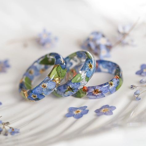 ❤️  A beautiful clear resin ring with encapsulated dried blue forget me not flowers and tiny green leaves inside. These tiny flowers come in beautiful blue colour, mixed with some green leaves and metal flakes which make the ring so magical and specially made for nature lovers. ❤️  This resin ring is perfect for stacking! It's smooth all the way around and it is so comfortable to wear. 🌳 All my resin rings are handmade with self-made molds. they are also hand-sanded and polished, to be smooth and comfortable to wear. Given the nature of the resin, my rings may contain tiny bubbles and imperfections, but I always try to make them as perfect as possible. The listing is for ONE ring. 🌳 MEASUREMENT Width: 5 mm/0.2 in Thickness: 2 mm/0.12 in 🌳 BUT, WHAT IS EPOXY RESIN? All my rings are handm Epoxy Resin Ring, Flower Resin Ideas, Forget Me Not Jewelry, Resin Ring Ideas, Epoxy Rings, Diy Resin Wall Art, Blue Forget Me Not Flowers, Epoxy Ring, Bio Jewelry