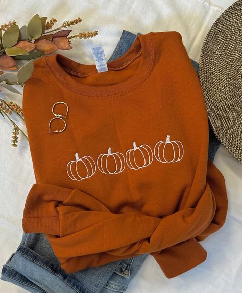 Cool Fall days and Pumpkin Patches, that's what we love!  The days become shorter but they sure seem to slow down.  Our simple pumpkin outline crew in the beautiful burnt orange is the perfect way to show you love the season in perfect minimalist style.  You will stay cozy and warm while looking super cute!   Pair with your favorite jeans, or size up one and grab your comfy leggings!  Features: 50% USA cotton, 50% polyester Pill-resistant air jet yarn Made with 50% sustainably and fairly grown U Cute Fall Crewneck Sweatshirt, Cozy Cute Fall Outfits, Fall Sweater Embroidery, Fall Graphic Sweatshirt, Cute Embroidered Shirts, Pumpkin Embroidery Designs, Fall Embroidery Designs Sweatshirt, Cute Fall Sweatshirts, Embroidered Halloween Sweatshirt