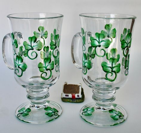 "Shamrocks of Irish green and white adorn this 5 7/8\" tall footed glass. These Irish Coffee Mugs hold 8 oz of your favorite beverage. A timeless vessel for coffee lovers of Irish whiskey or Irish Cream. If Irish tea is your bag, these are the glasses for you. 10 shamrocks color the bowl of the glass and there are an additional 3 shamrocks on the base. If you wish to have the glasses personalized, the information would go on the base instead of the shamrocks. Use with hot beverages or cold. Made Tall Mugs, Irish Tea, Gifts Boxes, March Birthday Gifts, Irish Coffee Mugs, White Petals, March Birthday, Glass Mugs, Hand Painted Vases