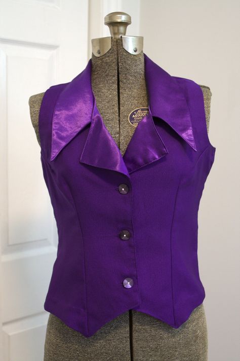 "A gorgeous purple waistcoat or vest made c. 1940s in silk cloqué, a fabric with a texture similar to crepe with one shiny side and one more matte side. This vest was made with the matte side on the outside, with the shiny inside showing on the turned-out lapels. Wide lapels with a deep notch and long points. Pointed centre front hems. Flower-shaped moonglow buttons with small rhinestone centres. This waistcoat probably originally formed part of a set with a skirt and perhaps a jacket. Condition Purple Alt Clothes, Purple Business Casual, Purple Outfits For Women, Green And Purple Outfit, Purple Skirt Outfit, Purple Steampunk, Purple Waistcoat, Purple Costume, Purple Clothes