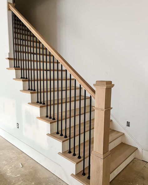 A neutral room features white stairs and oak wood treads. The oak is coordinated with a matching wood banister. Black railings contrast with the muted palette of the space. Wood Staircase Ideas, White And Wood Staircase, Wood Banister, Black And White Stairs, Black Staircase, Metal Stair Railing, White Staircase, Black Stairs, Stair Banister