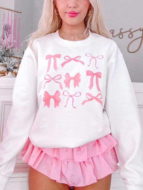 Meet the On Bow Nine Crewneck from Sassy Shortcake! This white sweatshirt is adorned with playful pink bows, bringing a touch of coquette charm to your outfit. She is soft, lightweight, and absolutely adorable! She is paired here with our light pink flirtatious skirt. Unisex crewneck sizing. Model is wearing a size small. Preppy Sweat Shirts, Birthday Outfits Preppy, Coquette Outfit Ideas Aesthetic, Flirtatious Skirt, Cute Pink Clothes, Cute Outfits Preppy, Bows Clothes, Pink Preppy Outfit, Sassy Clothes