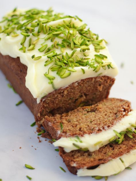 Side angle photo of baked courgette cake loaf topped with cream cheese icing and pistachio nut slices on white marble background. Courgette And Lime Cake, Courgette Cake Recipe, Courgette Cake, Pistachio Nut, Cake Recipes Easy, Vegetable Cake, Cake Loaf, Mascarpone Frosting, Side Angle