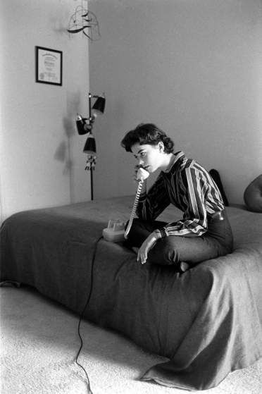 Natalie Wood takes a call while sitting on her bed at home in 1956. Someone Sitting On A Bed Reference, Sitting Upside Down On Couch, Poses With Furniture, Sitting Up In Bed Reference, Person Sitting Against Wall, Sitting In Bed Pose, Sitting On Bed Pose, Person On Phone, Man On Phone