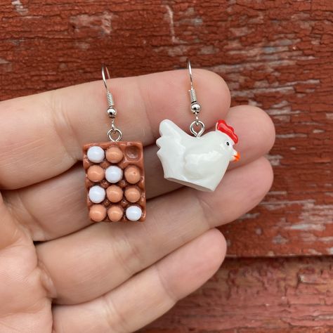 1 Pair of Mismatched Resin Chicken & A Carton Of Eggs Earrings  * Hypoallergenic Silver Plated * Ear Wires (Nickel & Lead Free, Tarnish & Rust Resistant, Great For Sensitive Ears) * Length: Chickens-2.25 Inches/Eggs 1.75 Inches * Width: Chickens 0.89 Inches/Eggs 0.60 Inches  * Lightweight: Chickens 1.95 Grams/Eggs 1.88 Grams * Silicone Stoppers Included What came first? The chicken or the egg? 🤔 Unmatched Earrings, Cute Fun Earrings, Chicken Clay, Novelty Earrings, Affordable Novelty Earrings, Food Earrings Clay, Chicken Earrings, Silly Earrings, Fried Egg Earrings