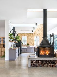 A Radiante 846 2V double- sided fireplace from Cheminées Philippe warms the living and kitchen areas; the neatly stacked woodpile adds a rustic note - HomesToLove.com.au Wood Storage Inside, Fireplace Between Kitchen And Living, Zen Books, Castle Cottage, Yoga Garden, Barn Loft, Cottage Plans, Double Sided Fireplace, Wood Heater