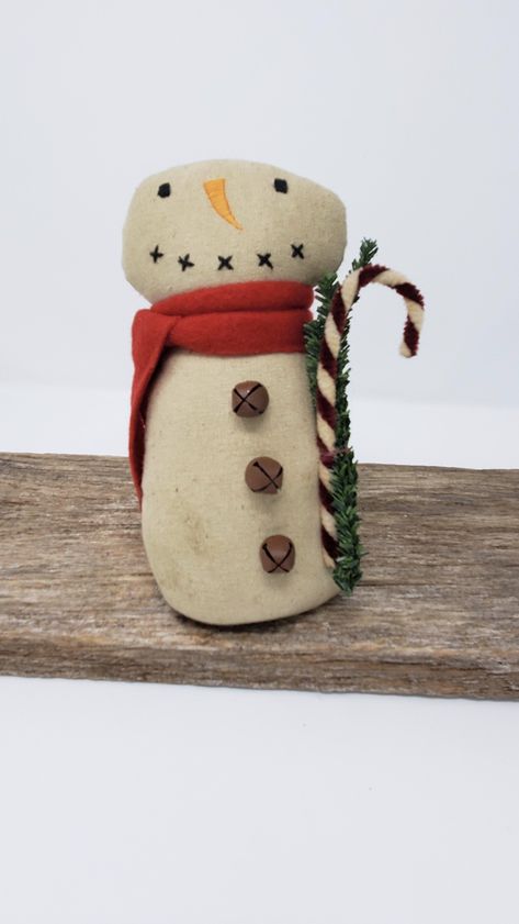 This adorable PRIMITIVE FABRIC SNOWMAN has a weighted, sand-filled bottom and is holding a chenille CANDY CANE. He has a primitively stitched face, wears a felt fabric scarf and has JINGLE BELL buttons. The perfect little SNOWMAN to add to your PRIMITIVE HOLIDAY DECOR Snowman measures 7" high x 3" wide x 2" deep. Primitive Snowmen Patterns, Fabric Snowman, Primitive Christmas Crafts, Painted Dolls, Christmas Primitive Crafts, Primitive Fabric, Small Snowman, Snow Men, Primitive Snowman