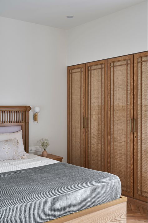 A solid teak wood bed with clean details on the back, adorned by a cane shuttered wardrobe. Cane Wardrobe, Cane Bedroom, Teak Wood Bed, Chettinad House, Bespoke Chair, Light Chair, Bed Apartment, Wardrobe Designs, Wood Bed