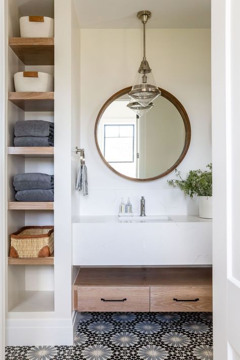 Modern and bright bathroom with built in towel storage, blue patterned floor and custom floating vanity.