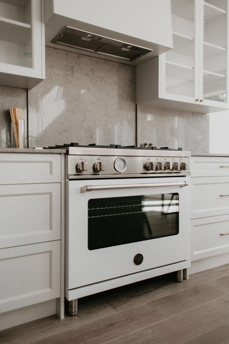 This classic kitchen features a Bertazzoni 36" Master Series range front and center, complemented by a stone backsplash and light cabinetry. Stainless steel accents pair with wood flooring to create a calming kitchen atmosphere. The overall aesthetic speaks to the Parisian design sensibility throughout the home.     (Builder + Design: Bloc53 Developments / Repost: Yeg infill / Photographer: Sharon Litchfield) Bertazonni Range Kitchen, Bertazonni Kitchen, White Kitchen Stone Backsplash, Bertazzoni Range Kitchen, Calming Kitchen, Mandi Design, Bertazzoni Kitchen, Bertazzoni Range, Range Kitchen