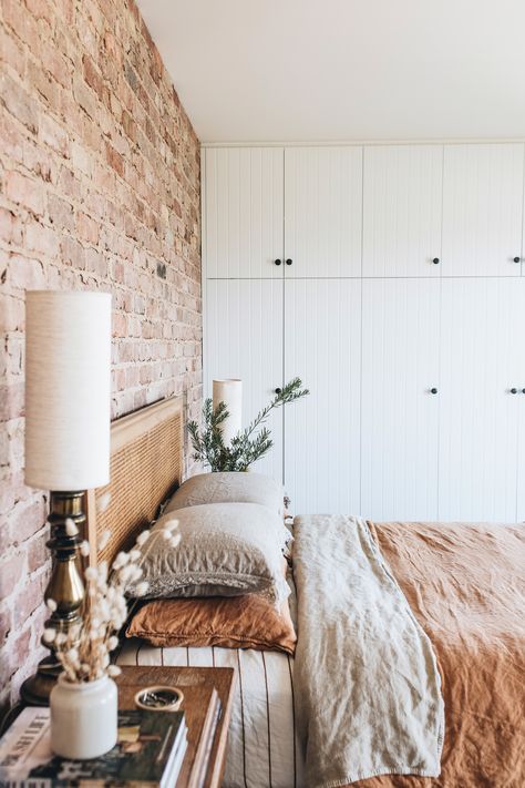 The bedroom of this modern country home in Tasmania features an exposed brick wall and linen sheets. Boho Bedroom With Brick Wall, Australian Country Bedroom, Bedroom With Exposed Brick, Brick Wall In Bedroom, Brick Wall Interior Bedroom, Country Modern Bedroom, Red Brick Bedroom, Exposed Brick Walls Bedroom, Brick Wall Feature