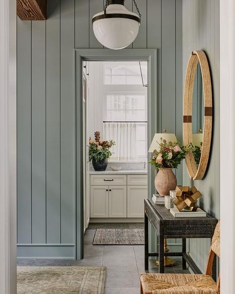 Blue shiplap trim accents a foyer boasting a black cane console table, styled and located under a round brown mirror. Cottage Paint Colors Interior, Mudroom Paint, Mudroom Paint Color, Benjamin Moore Bedroom, Entryway Colors, Entryway Paint, Entryway Paint Colors, Cottage Paint Colors, Green Grey Paint