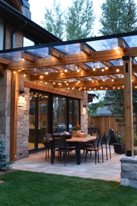 Backyard patio with a wooden pergola adorned with string lights over an outdoor dining area. Non Covered Patio Ideas, Pergola Ideas Attached To House Deck, Cover Deck Ideas On A Budget, Clear Roof Pergola Covered Patios, Patio Gable Roof Ideas, Metal Patio Covers Attached To House, Deck With Roof Covered Patios, Covered Gazebo Ideas, Backyard Covered Patio Designs Layout