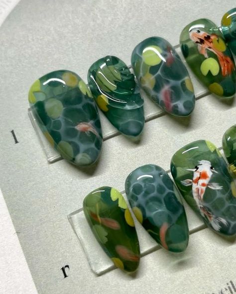 Veiled Nails on Instagram: "𝒌𝒐𝒊 🎏  Been wanting to do a koi fish set in a while! Complete with waterlilies 😌  ✦ 𝑺𝒊𝒛𝒆 𝒂𝒏𝒅 𝑺𝒉𝒂𝒑𝒆 - Medium Almond Natural @apresnailofficial ✦ 𝑭𝒍𝒂𝒔𝒉 𝑺𝒆𝒕  ✦ Using @sweetienailsupply Jin.B Crazy Top and @agehagel @trinagel_official  colours 。 。 。 。 。 。 #koinails #fishnails #koifishnails #koipond  #水墨画 #handpainted #3dnails #3dnailart #3dネイル #うるうるネイル #bluenails #nuancenails #pressons #veilednails #pressonnails #waternails #clearnails #greennails" Water Lily Nail Art, Pond Nail Art, Nails With Fish, Koi Pond Nails, Goldfish Nails, Koi Fish Nail Art, Pond Nails, Koi Nails, Koi Fish Nails