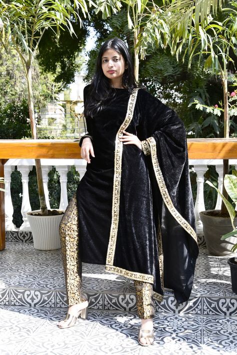 An elegant black straight-cut ladies suit set in velvet fabric, with boat neckline and full fitted sleeve that has beautiful gold embroidery lace on sleeve hemline. It is gracefully paired with a fine black silk jacquard trouser and a black velvet dupatta with gold embroidered lace on alll sides Black Velvet Dupatta, Indian Clothing Brands, Velvet Dupatta, Ethnic Wear Indian, Ladies Suit, Indian Clothing, Gold Embroidery, Embroidery Lace, Boat Neckline